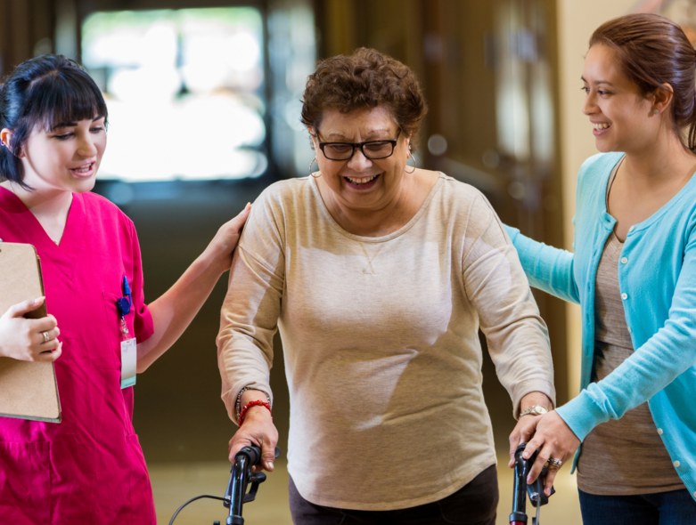 Caregivers walking alongside a smiling resident